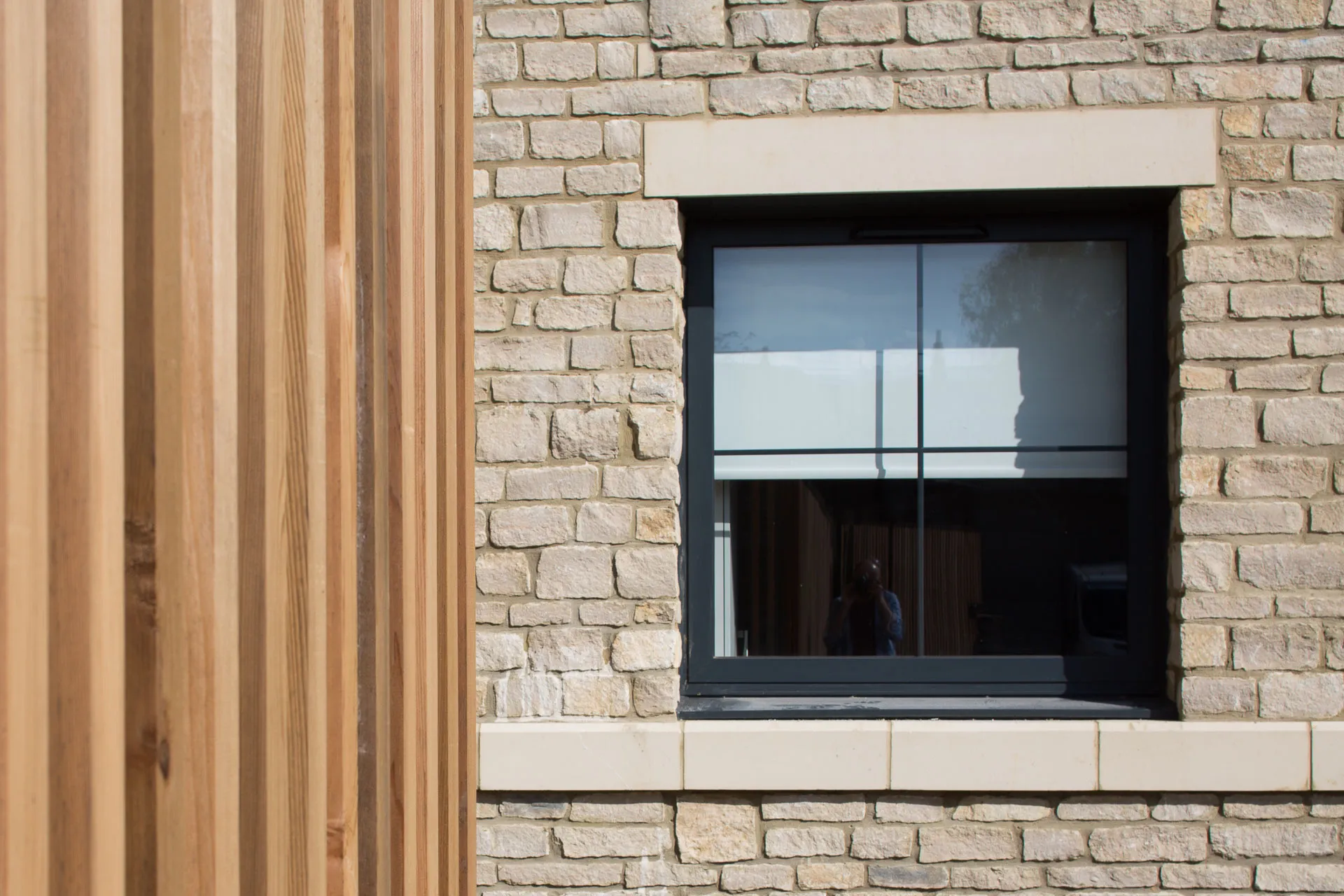 Timber cladding meeting stone and a black-framed window, Weirside Court